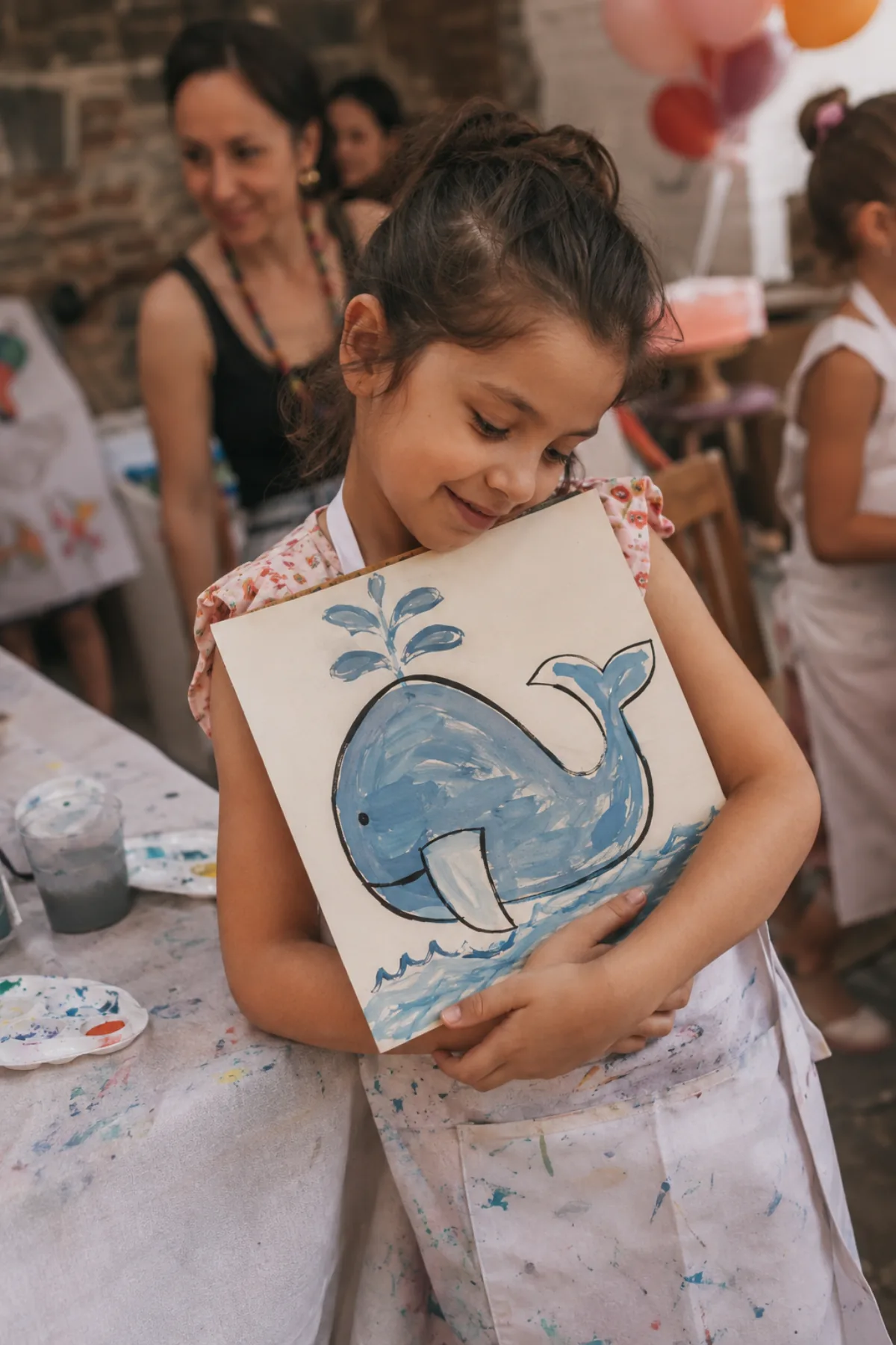 Niña abrazando su pintura terminada de una ballena